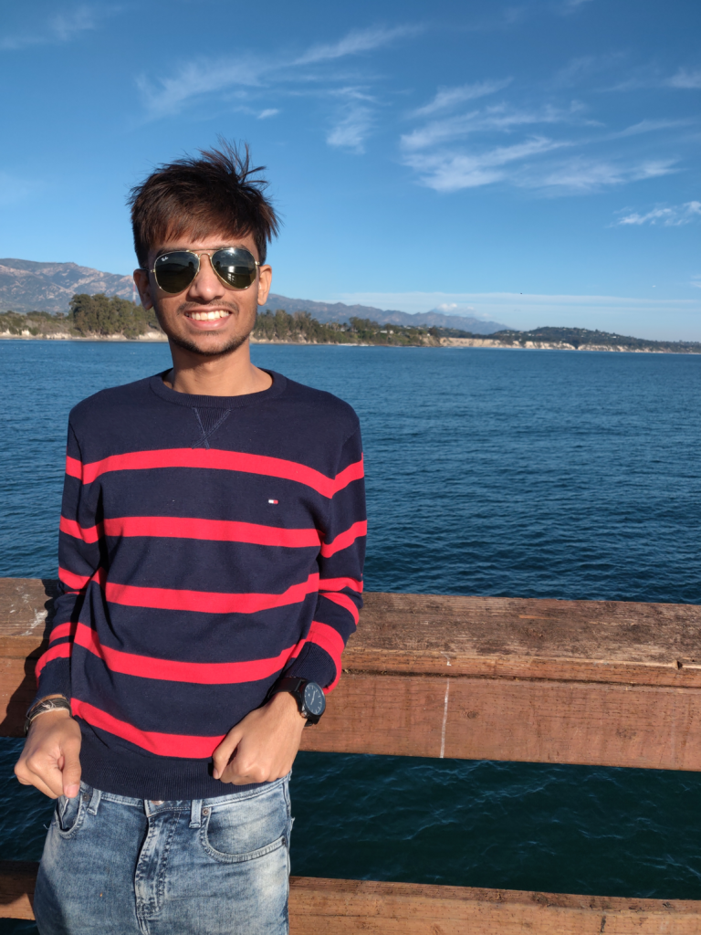 Young South Asian man in front of a lake.