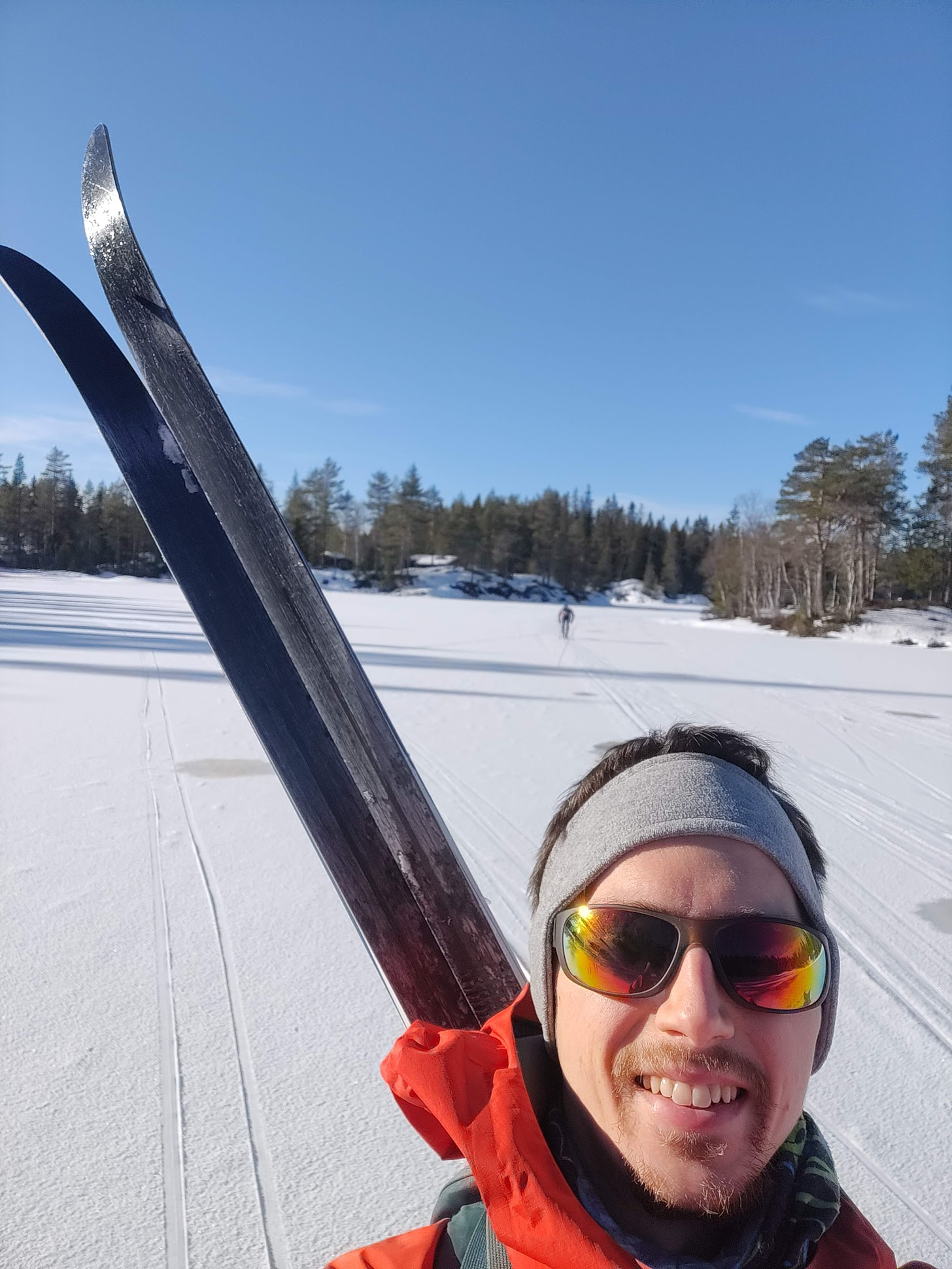 Young bearded man with skis on slope.